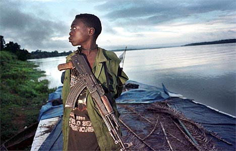 DONGO, CONGO.  SEPTEMBER 15, 2000: A young soldier with the MLC  (Movement for the Liberation of Congo), a rebel army, rides atop a boat on the Ubangi River approaching the remote village of Dongo in northwestern Congo, where they recently made a significant advance against President Laurent Kabila's army.   (Photo: Tyler Hicks/Liaison).